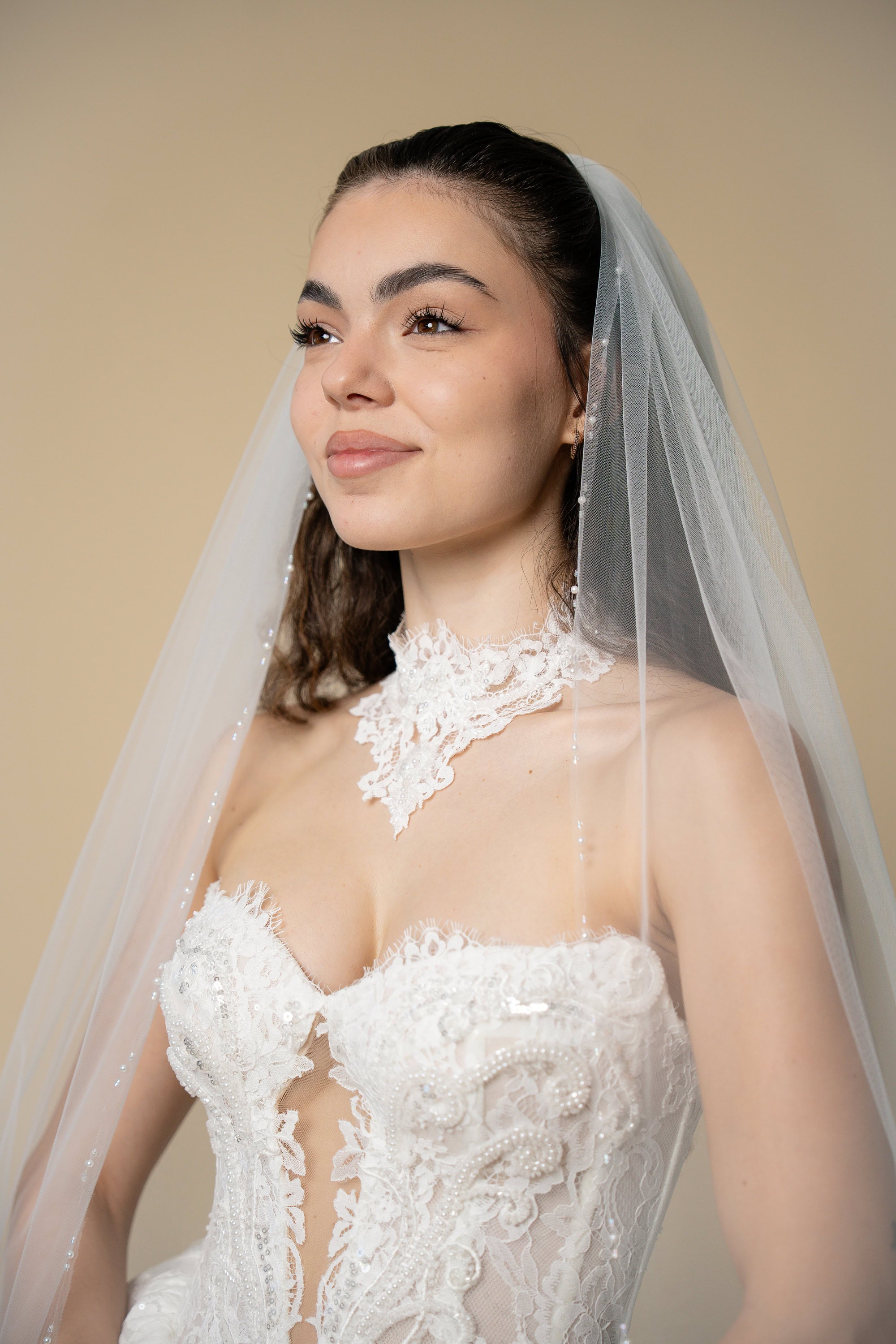 Elegant bride wearing the Edith pearl and crystal bridal veil with refined linear bead detailing by Aoura Veil