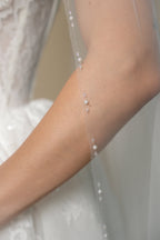 Close-up of the Edith cathedral wedding veil featuring linear groups of pearls and crystal beads along the edge by Aoura Veil