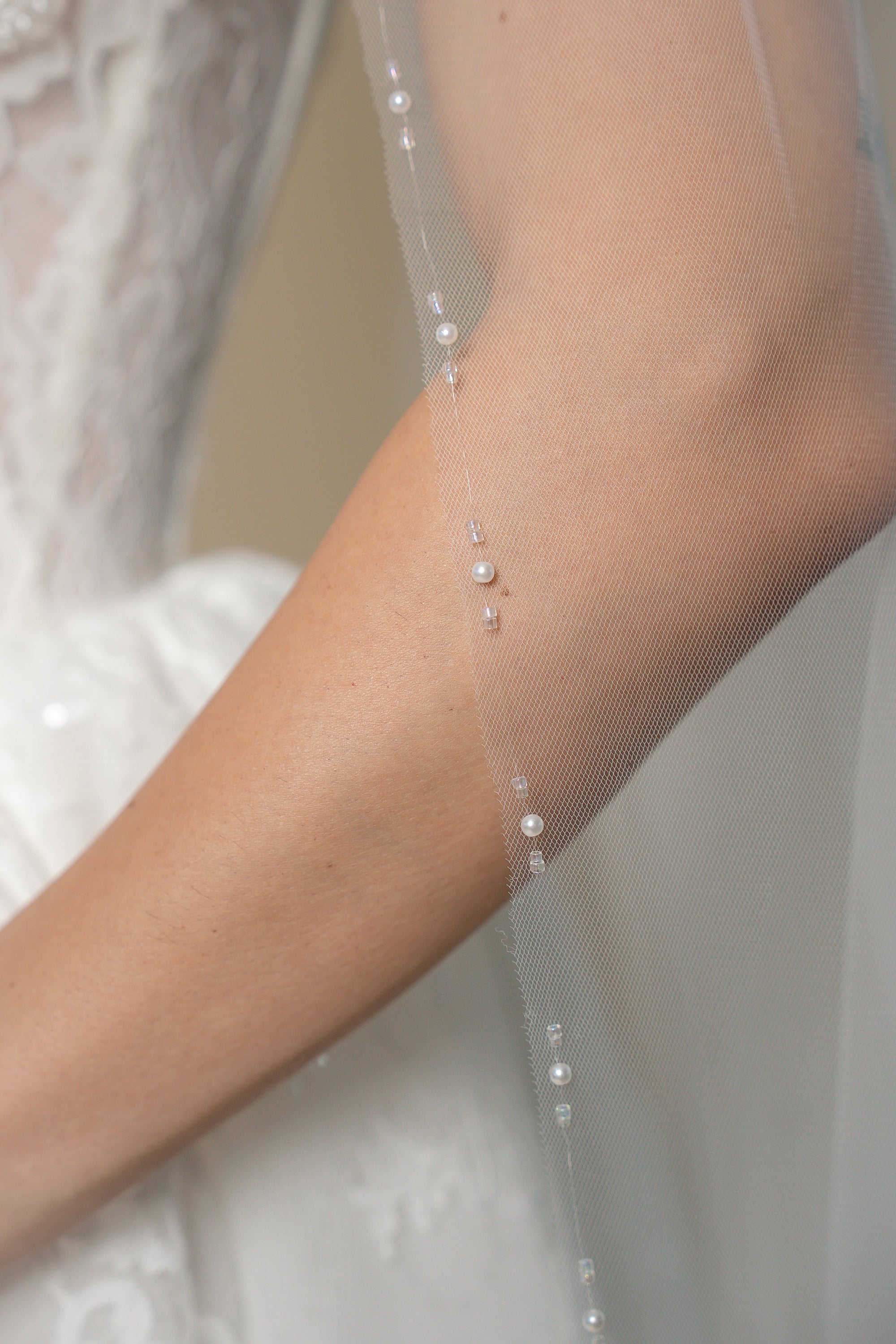 Close-up of the Edith cathedral wedding veil featuring linear groups of pearls and crystal beads along the edge by Aoura Veil