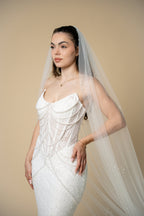 Bride wearing the Poppy pearl cathedral wedding veil decorated with elegant pearl clusters across the entire veil by Aoura Veil