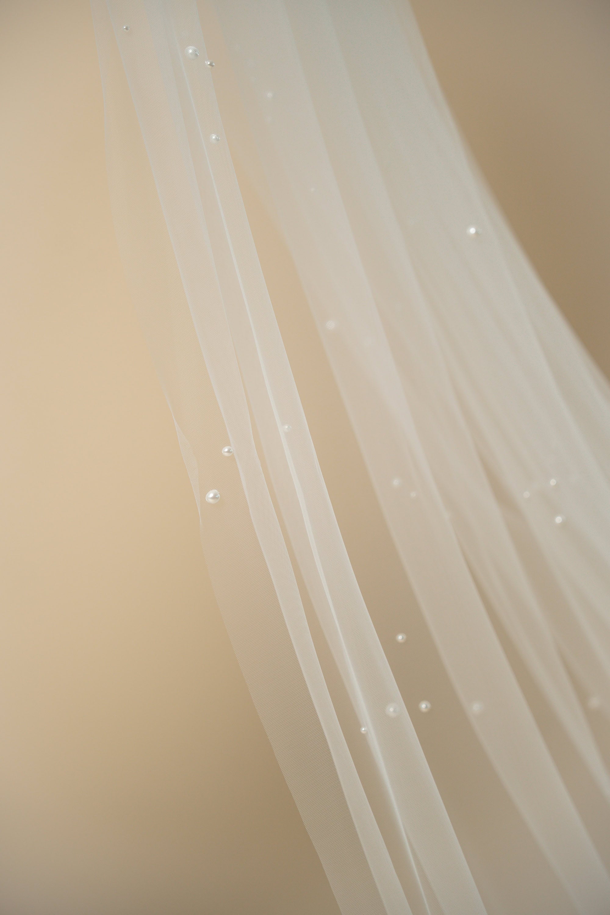 Close-up of the Poppy bridal veil showcasing handcrafted pearl clusters delicately attached across the tulle by Aoura Veil
