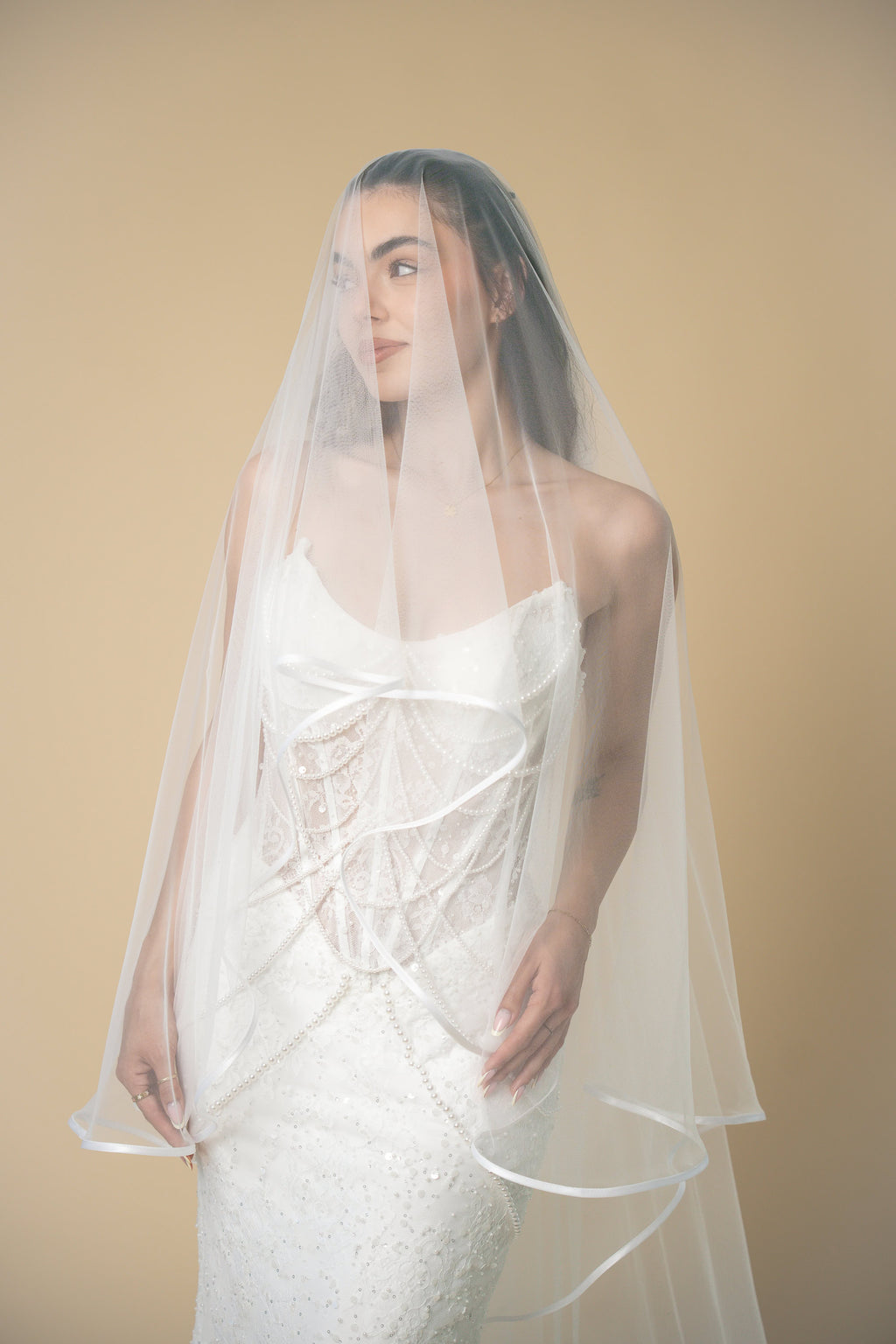 Bride wearing the Vivian cathedral wedding veil with a soft white satin edge and elegant blusher by Aoura Veil