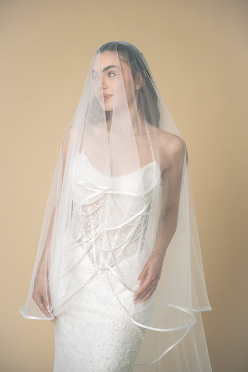 Bride wearing the Vivian cathedral wedding veil with a soft white satin edge and elegant blusher by Aoura Veil